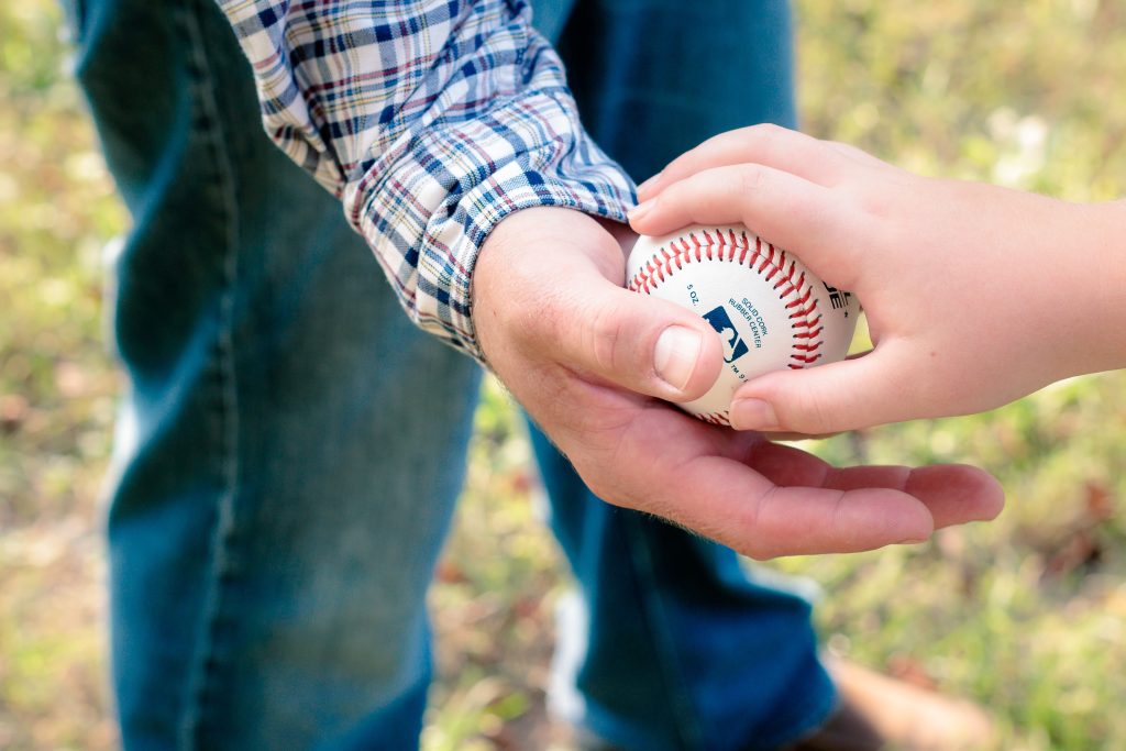 The Hidden Marketing Power of Seasonal Rituals: Lessons from the MLB Playoffs A close-up of a father and son passing a baseball outdoors on a sunny day.
