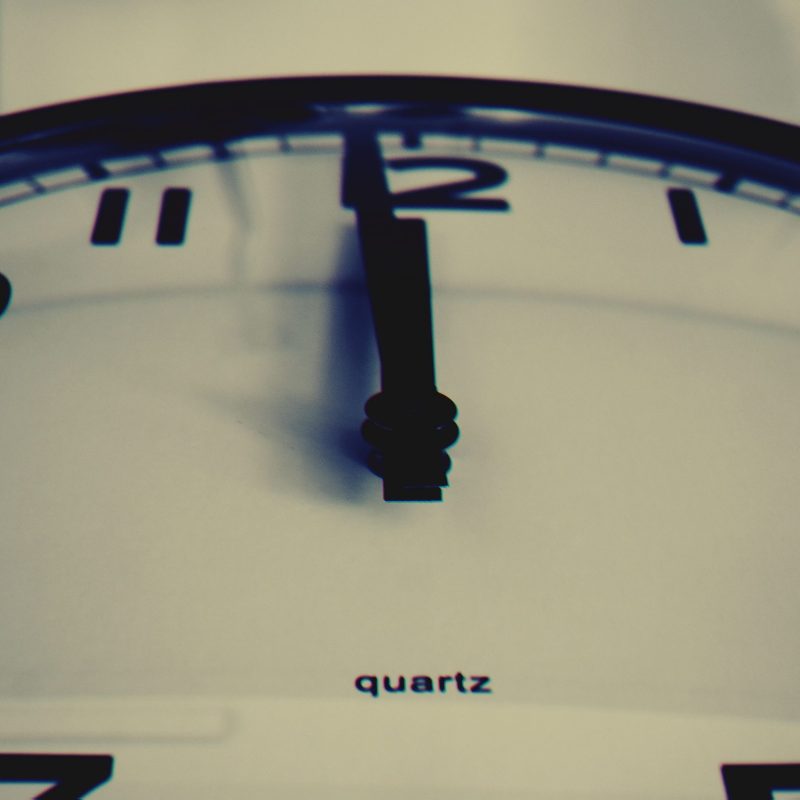Detailed close-up shot of a wall clock showing the hour hand at midnight, highlighting time concept.